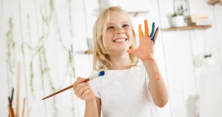 arte e scuola - bimba che tiene un pennello ed ha le mani sporche di colore arte nelle scuole