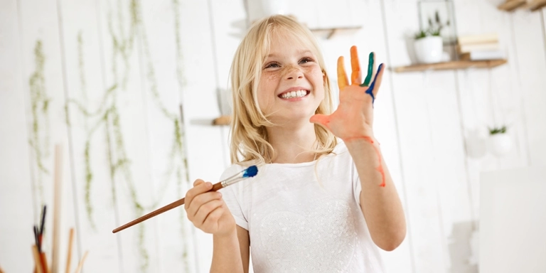 arte e scuola - bimba che tiene un pennello ed ha le mani sporche di colore arte nelle scuole